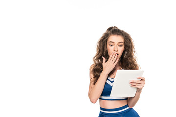 shocked cheerleader girl in blue uniform holding digital tablet isolated on white