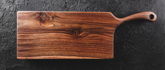 Chopping cutting board on dark stone background. Wooden texture. Top view, toning