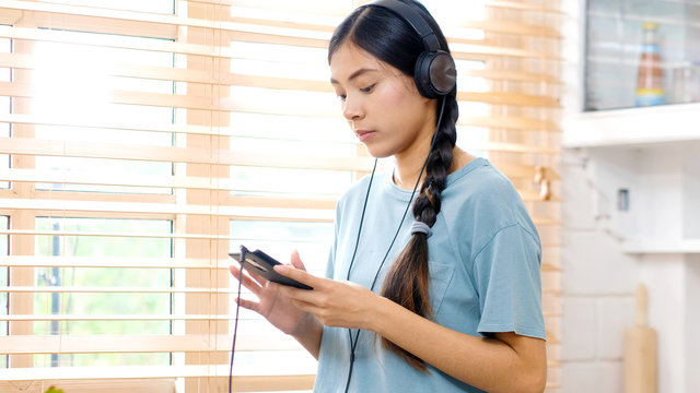 Asian woman with headphones listening music using smartphone app, Teenager asian girl and headset when listening music, Beautiful woman with headphones listen to with music by smartphone app