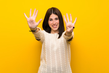 Young woman over isolated yellow wall counting nine with fingers