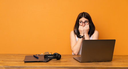 Business woman in a office nervous and scared putting hands to mouth
