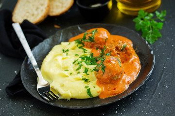 Meatballs in creamy tomato sauce with mashed potatoes.