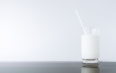 Glass of milk on black reflex table and isolated on white background