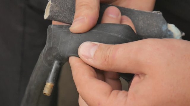 Cyclist or mechanic cleans a punctured tire bicycle. Close up of hands and bicycle flat tire tyre. A man repairs a bicycle wheel pierced.