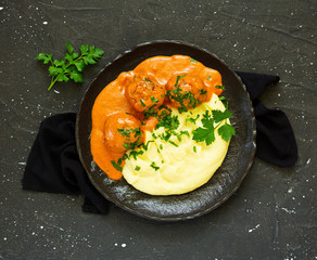 Meatballs in creamy tomato sauce with mashed potatoes.
