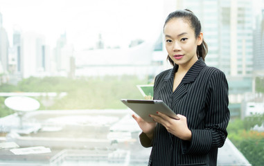 An asian business woman is using tablet beside window