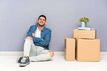 Handsome young man moving in new home among boxes laughing