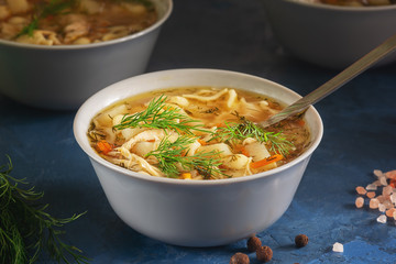 Fresh Chicken Noodle Soup Ceramic Bowl Closeup. Full Dish of Meat Broth with Pasta and Vegetables. Healthy Diet. Hot Poultry Pepper Condiment Bouillon. Appetizing Homemade Lunch on Kitchen Table