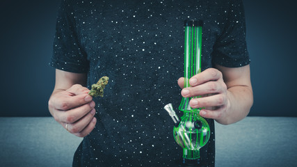 The young person hold in his hand medical marijuana buds and bong. Smoking medical cannabis with...