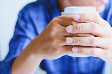Close-up business man hand holding coffee cup and thinking creative work in home office.