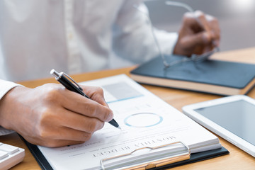 Close-up of hands Businessman reading and writing with pen signing contract over document for Completing Application Form at work in office.