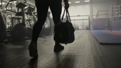 Confident brutal man holding bag and coming to the gym to workout, sport and bodybuilding concept. Action. Back view of a sportsman wearing tracksuit at the gym.