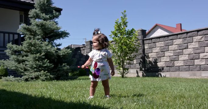 A little girl wears summer clothes with a windmill in her hand