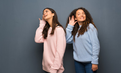 Teenager friends listening to something by putting hand on the ear