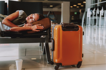 Exhausted young girl is sleeping at airport