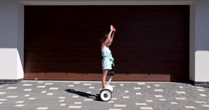 Little Girl rides a gyroscooter near the garage