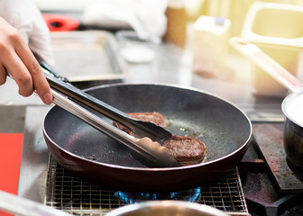 Fry the meat in a frying pan. Chef preparing and spicing meat restaurant kitchen