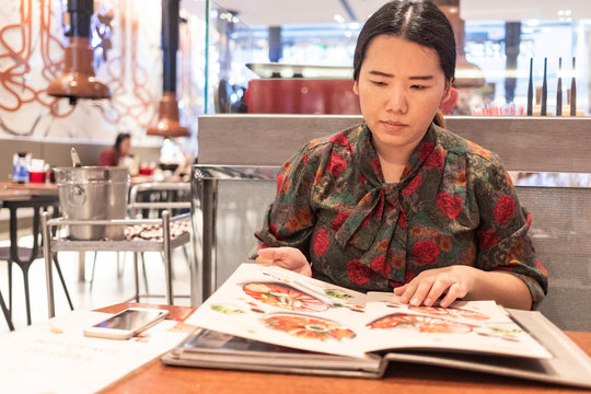 Bangkok, Thailand, Jul 14, 2019 - Asian Woman Looking At The Menu Before Order Food In Japanese Restaurant