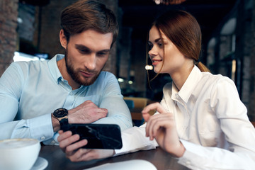 man and woman working on tablet computer in cafe