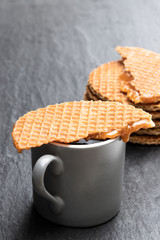 Melted Dutch caramel waffles with cup of coffee on black stone background