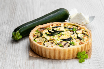 Homemade courgette and feta quiche on white wooden table