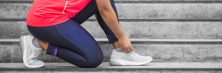Woman tying shoelace on running shoes before practice. Runner getting ready for training. Sport active lifestyle concept.  Outdoor workout concept for web banner, website page etc.