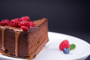 Piece of chocolate cheesecake with berries on dark background