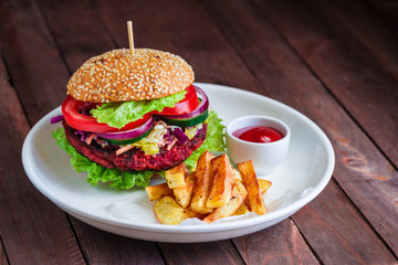 healthy burger with beet cutlet vegetables fries potato sauce bowl on white plate on wooden table