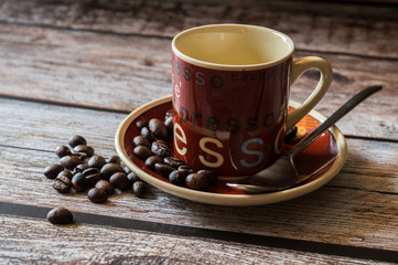 Tazza di caffè con grani sparsi sul tavolo di legno 