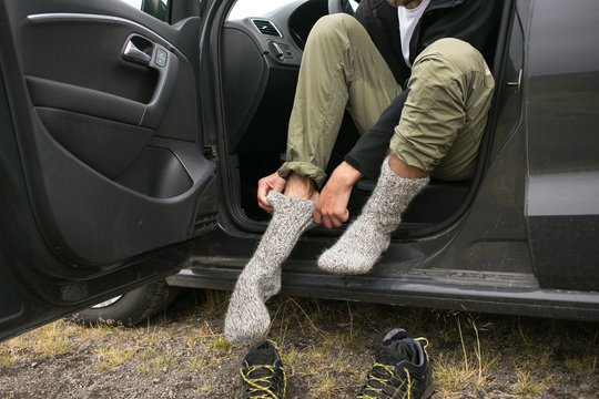 Adventurer, touirst or hiking affectionate changes shoes inside car after or before long wet walk in harsh conditions. Puts on pair or clean and dry wool socks to warm up feet in cold weather