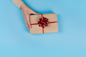 Womans hands holding gift or present box on blue pastel table. Flat lay  for birthday or New Year.