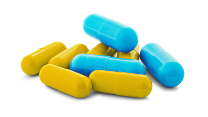 Pile of medical pills in yellow and blue colors on white isolated background with shadow.