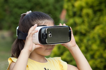 Cute little boy using VR glasses outdoors in a park - Blogger testing augmented reality goggles...