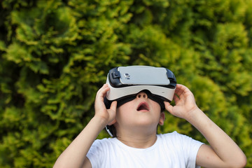 Cute little boy using VR glasses outdoors in a park - Blogger testing augmented reality goggles concept - Gamer exulting during 3D video game playing 
