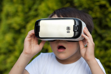 Cute little boy using VR glasses outdoors in a park - Blogger testing augmented reality goggles...