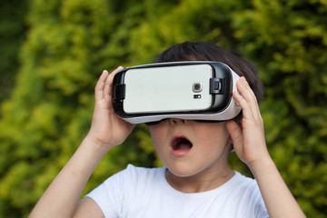 Cute little boy using VR glasses outdoors in a park - Blogger testing augmented reality goggles concept - Gamer exulting during 3D video game playing 