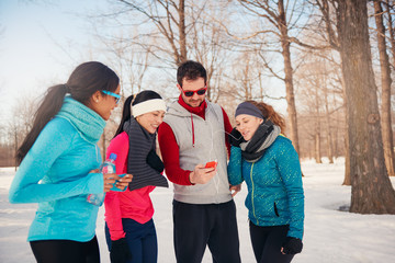 Group of friends listening to music in the snow in winter