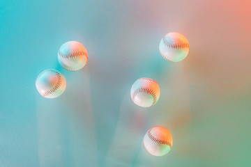 top view of white and leather softballs on pink and blue