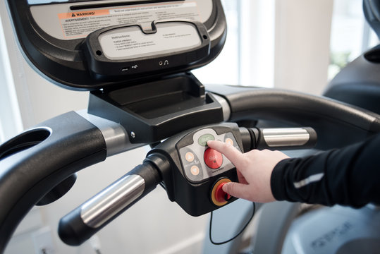 Detail of hand pressing start button on treadmill
