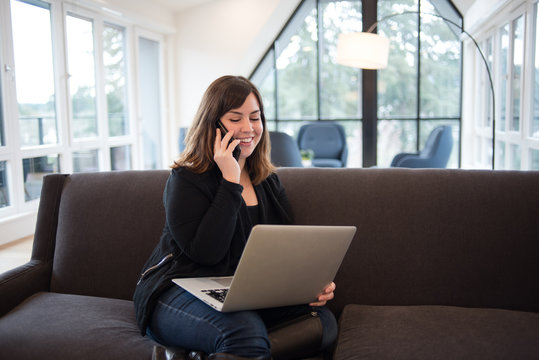 Woman talking on phone and using laptop computer