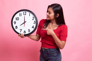 Young Asian woman point to a clock.