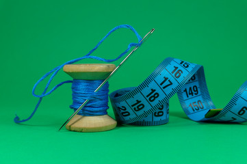 Blue thread, tape measure and sewing needle