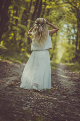 adorable blond girl walking in sunny day in magical forest