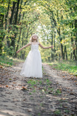 adorable blond girl walking in sunny day in magical forest