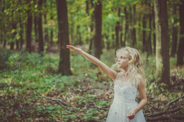 adorable child in long white wedding dress with butterfly in hands