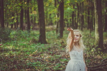 adorable child in long white wedding dress with butterfly in hands