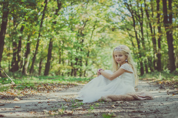 Fototapeta na wymiar romantic child sitting in princess dress under the trees