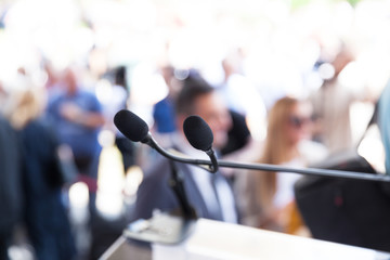 Microphone in focus at media or public event, blurred people in the background