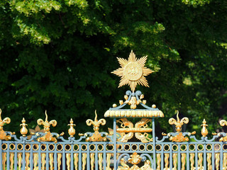 Fototapeta premium Fragment of the fence of Charlottenburg Palace, Berlin, Germany. Schloss Charlottenburg. Green garden, linden trees