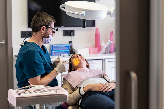 Dentist with a precision glsses smiling with patient in dental clinic. - Powered by Adobe
